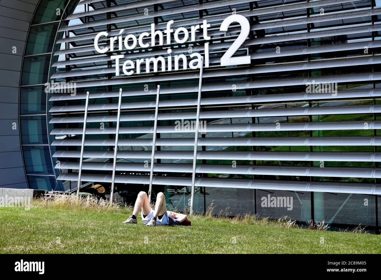 New Terminal 2, T2 Criochfort Dublin International Airport DUB. Young man in shorts, rests, lying on the grass. Republic of Ireland, Europe, EU. Stock Photo