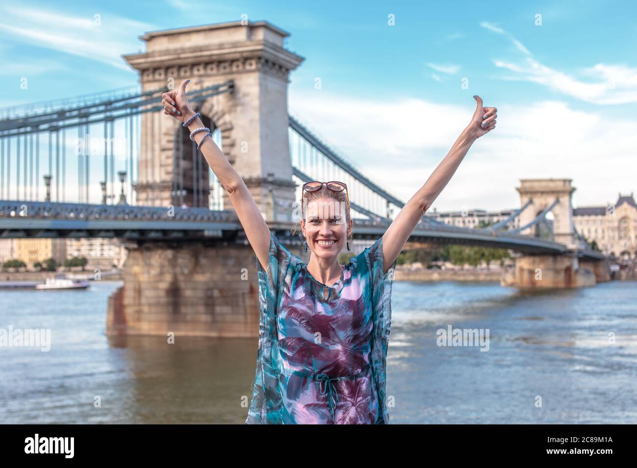 Happy young woman arms raised at Chain Bridge, Budapest, Hungary Stock Photo