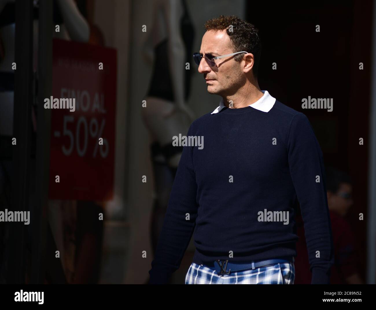Italian man walking nearby clothes stores, with showcases announcing discounts. Via Sparano da Bari, Bari, Italy Stock Photo