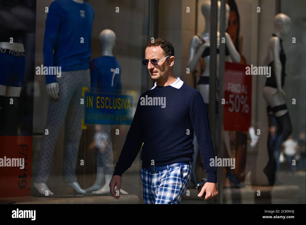 Italian man walking nearby clothes stores, with showcases announcing discounts. Via Sparano da Bari, Bari, Italy Stock Photo