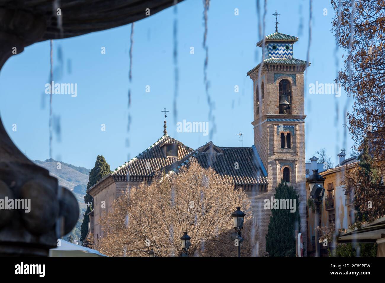 View of the church of Santa Ana de Granada after the jets of water from the Plaza Nueva fountain Stock Photo