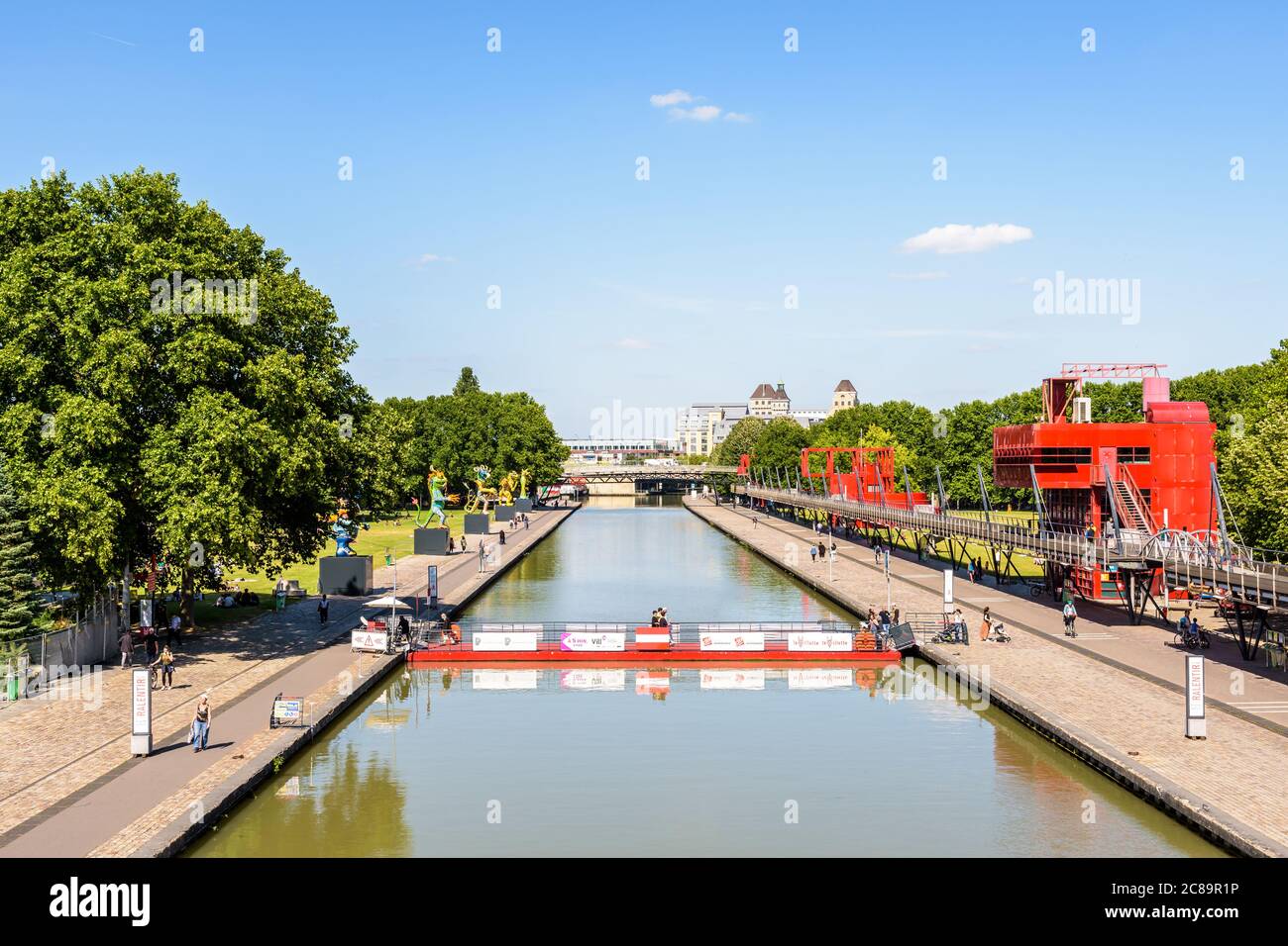 The Canal de l'Ourcq splits the parc de la Villette in Paris, France, crossed by a mobile floating footbridge and bordered by statues and follies. Stock Photo