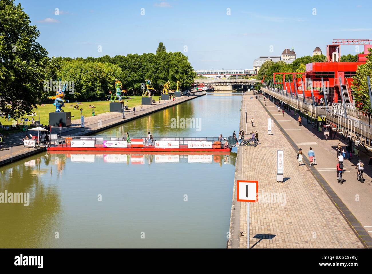 The Canal de l'Ourcq splits the parc de la Villette in Paris, France, crossed by a mobile floating footbridge and bordered by statues and follies. Stock Photo