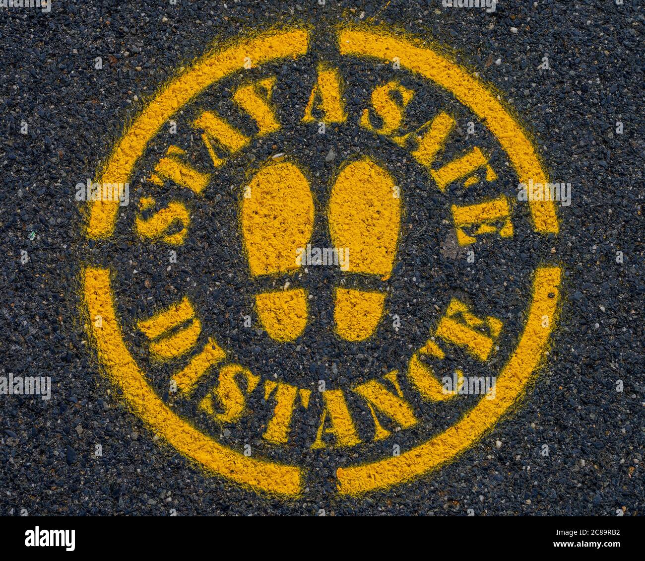 Covid-19 Stay a Safe Distance Sign on the pavement or road. Stock Photo