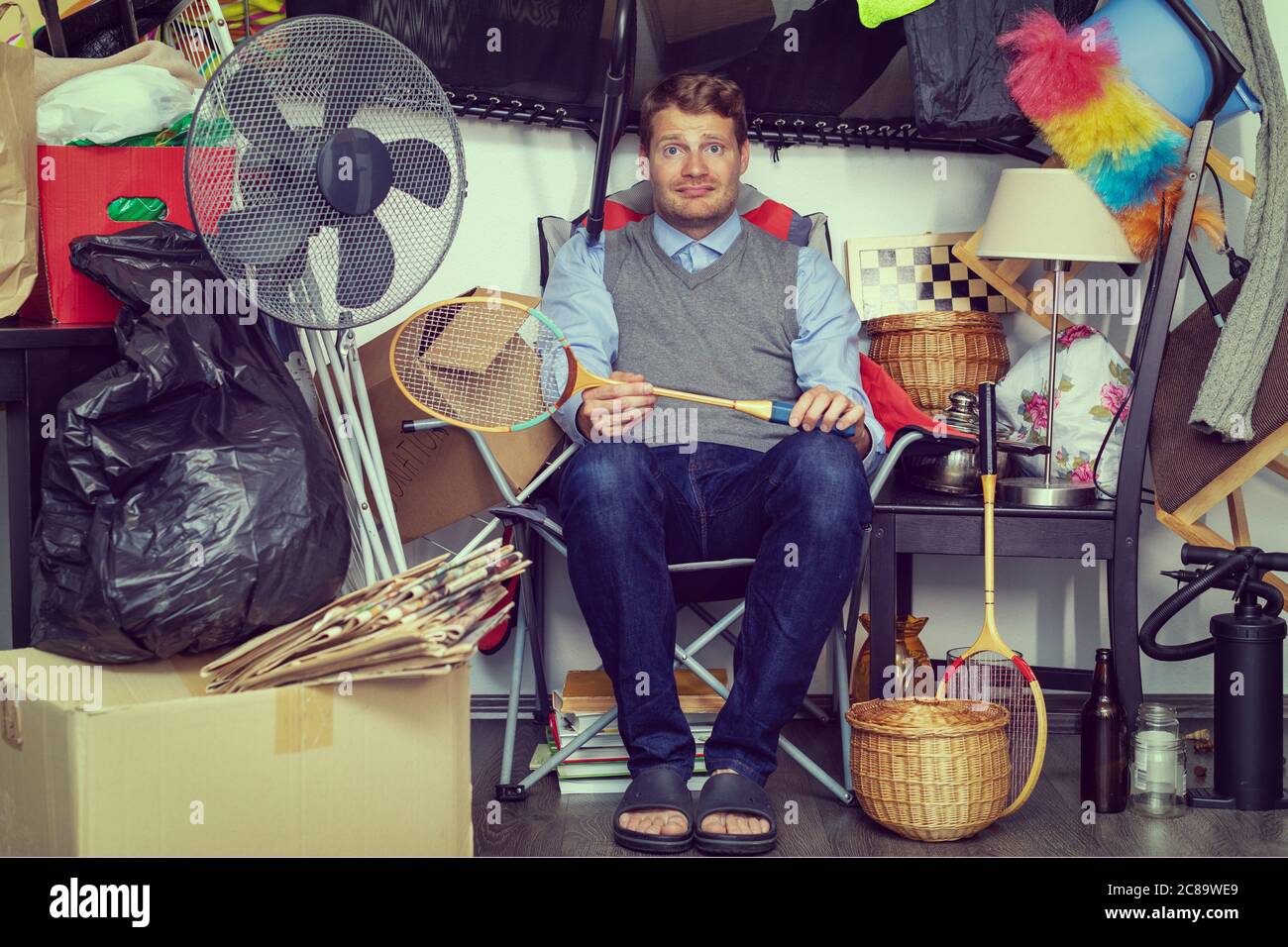 compulsive hoarding disorder concept - man hoarder with stuff piles sitting in the room Stock Photo