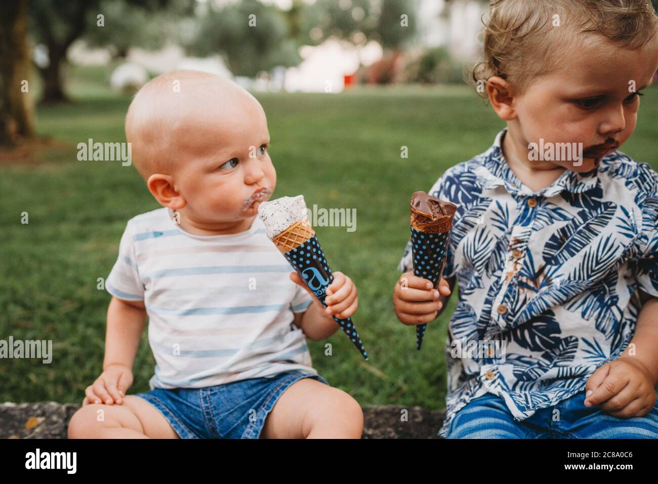Young white toddler and baby eating ice cream in the summer Stock Photo