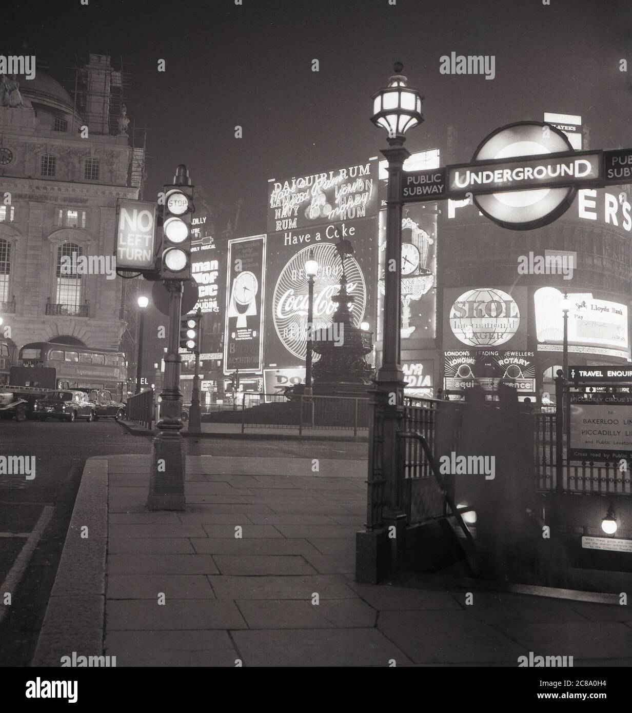 1960s, historical, a view of Piccadilly Circus, Westminster, London, England, UK, showing the famous neon billboards or advertising signs lit-up on the buildings at the roundabout and an entrance to the London Underground, the city's public subway or metro. Stock Photo