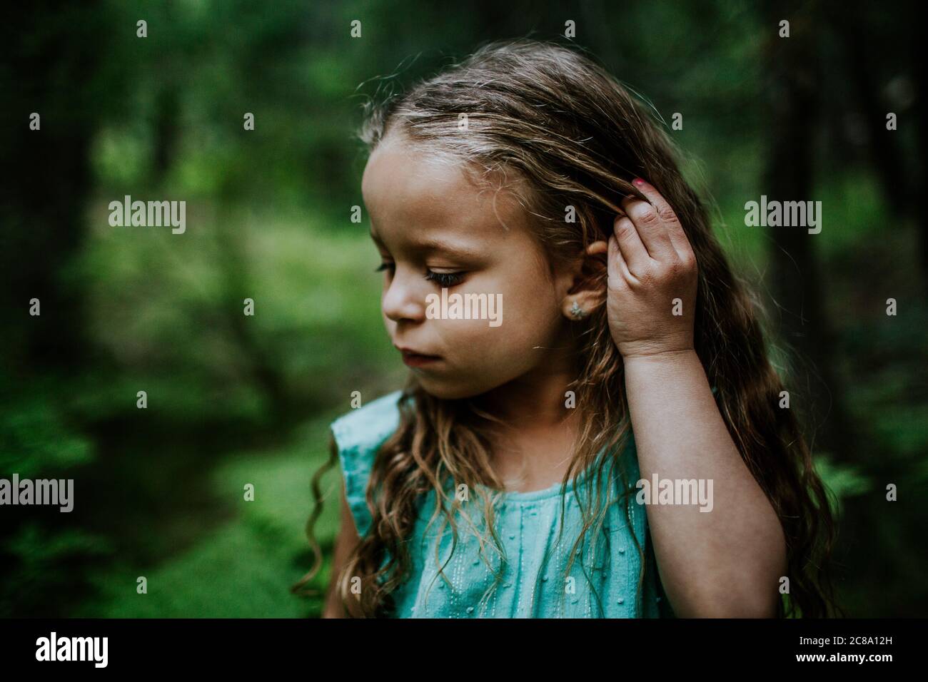 Young biracial girl looking down and fixing hair Stock Photo