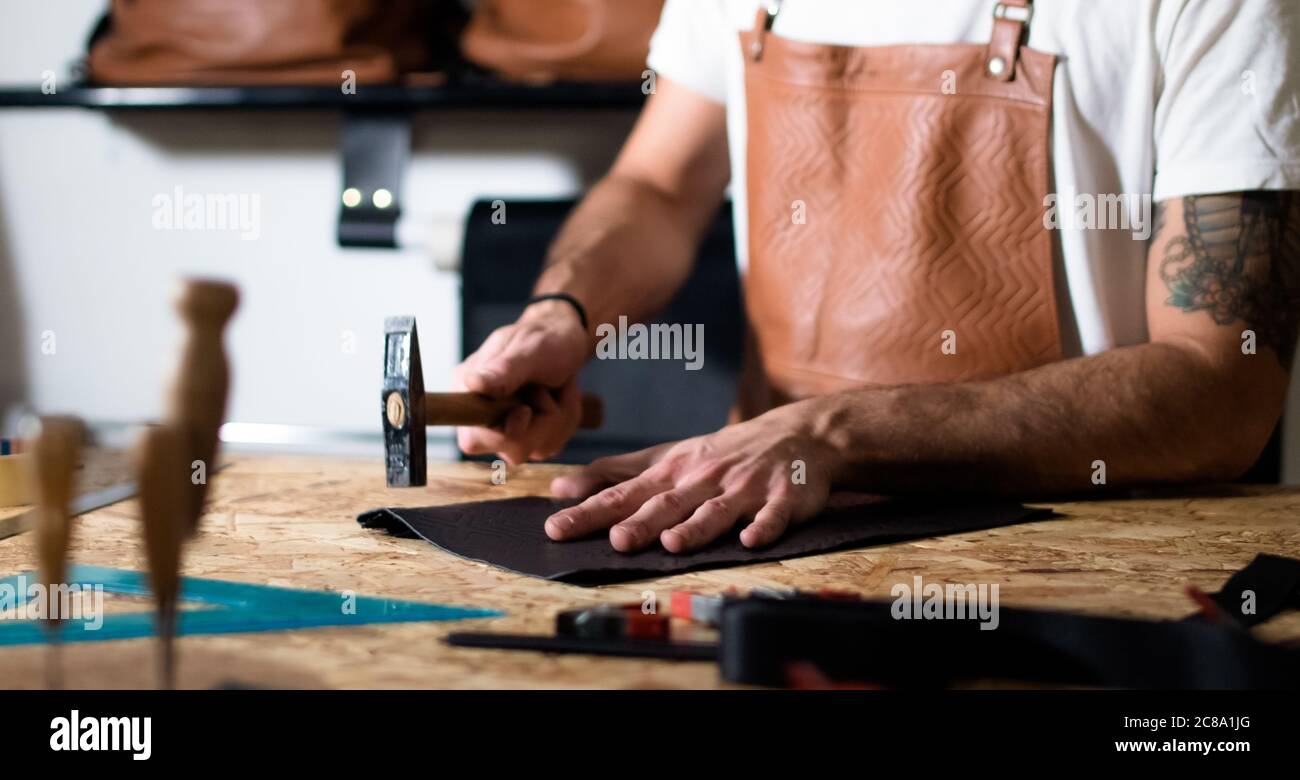 craftsman working with hands and hammer on leather Stock Photo