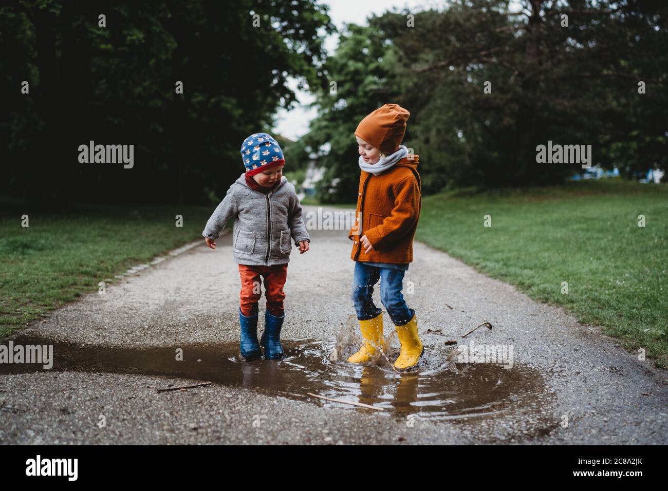 Male children jumping in the puddles at the park on rainy day Stock ...