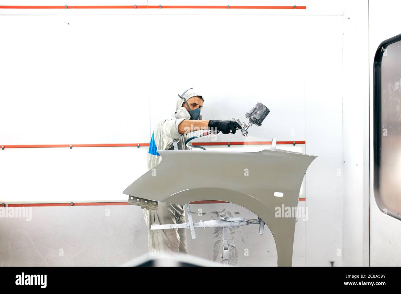 young painter Man with protective clothes and mask painting car detail