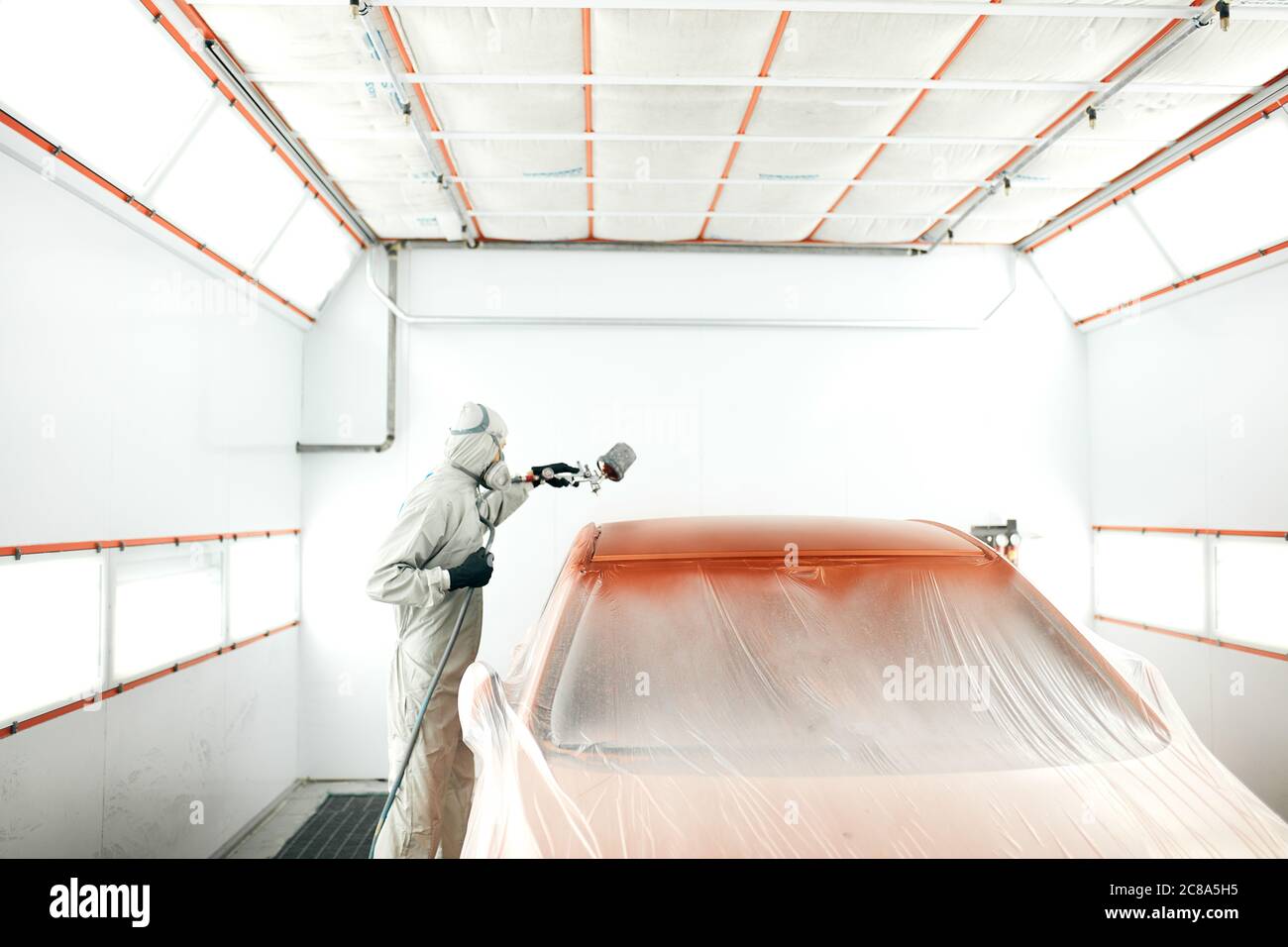 Car body painter spraying paint in garage or with airbrush