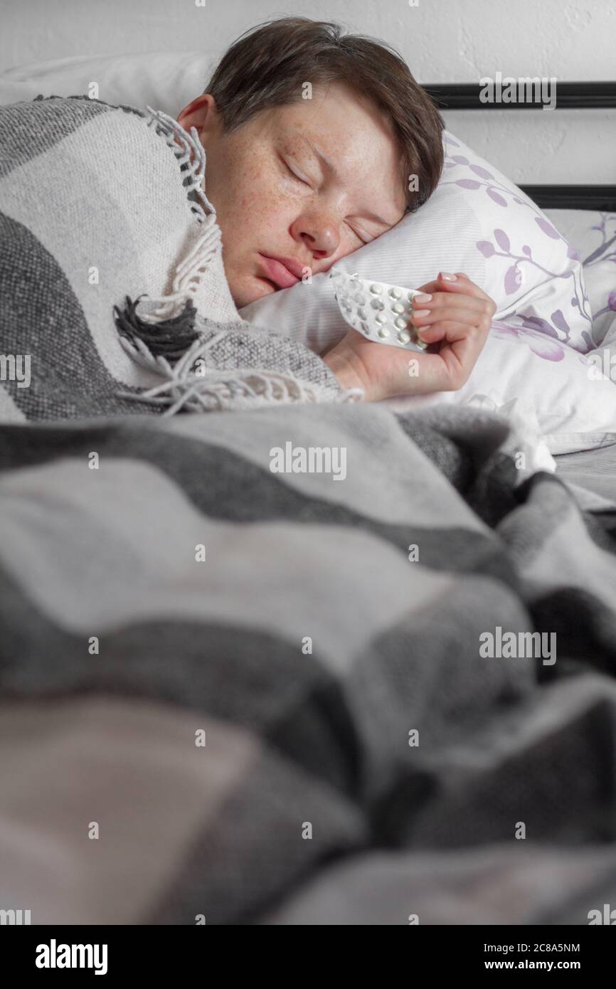 Mature brunette woman sleeping in bed under plaid blanket, concept of illness or cold, treatment at home, selective focus Stock Photo