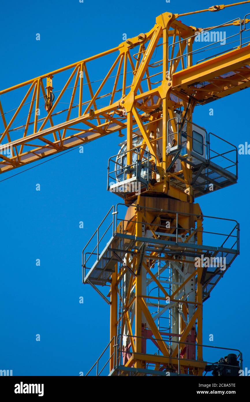 Yellow tower crane working on building against blue sky, selective focuse Stock Photo