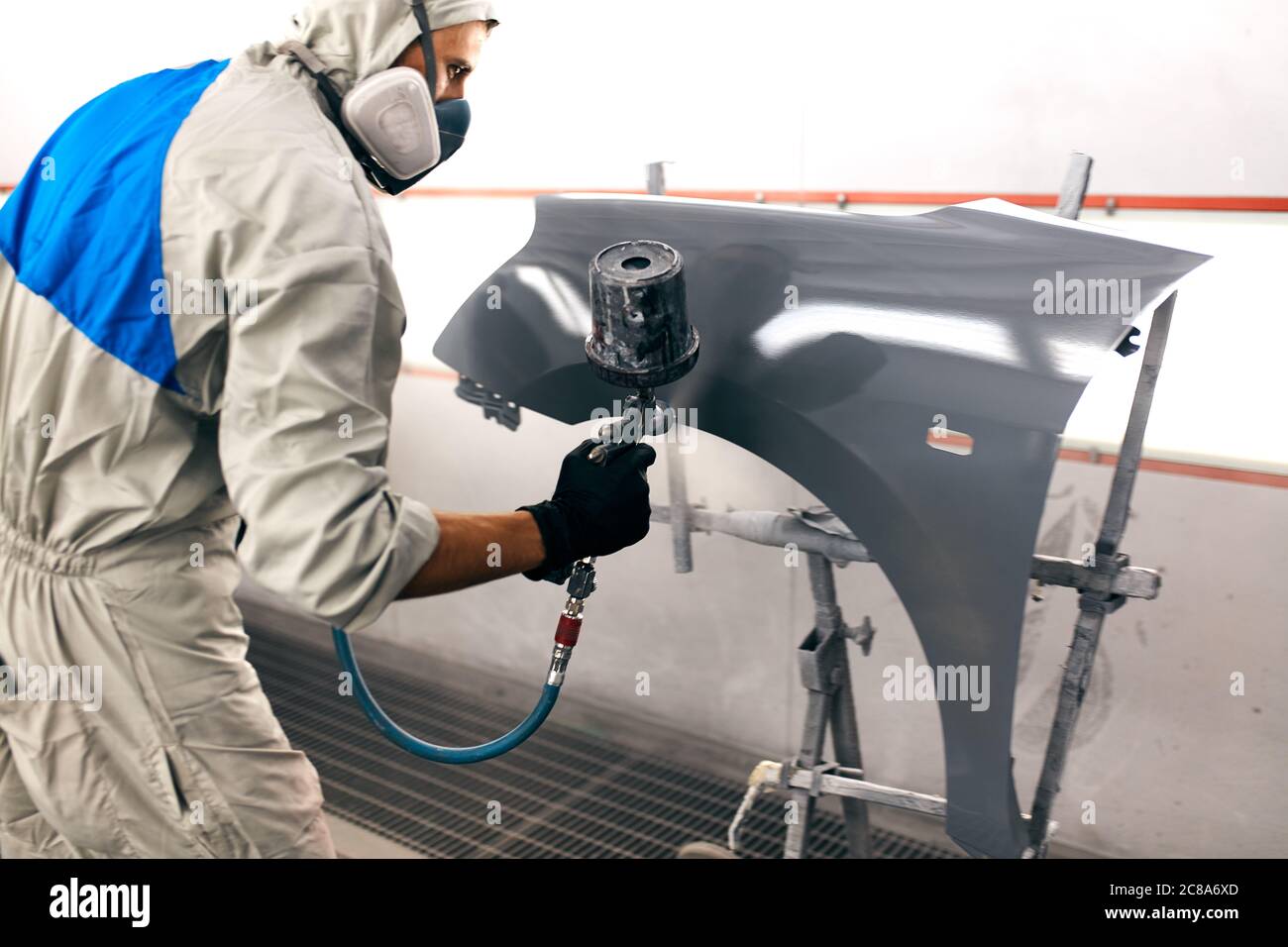 young painter Man with protective clothes and mask painting car detail ...