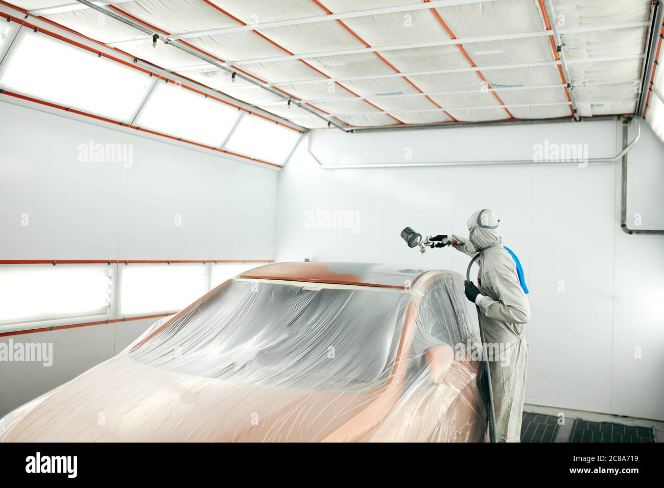 Car body painter spraying paint in garage or with airbrush