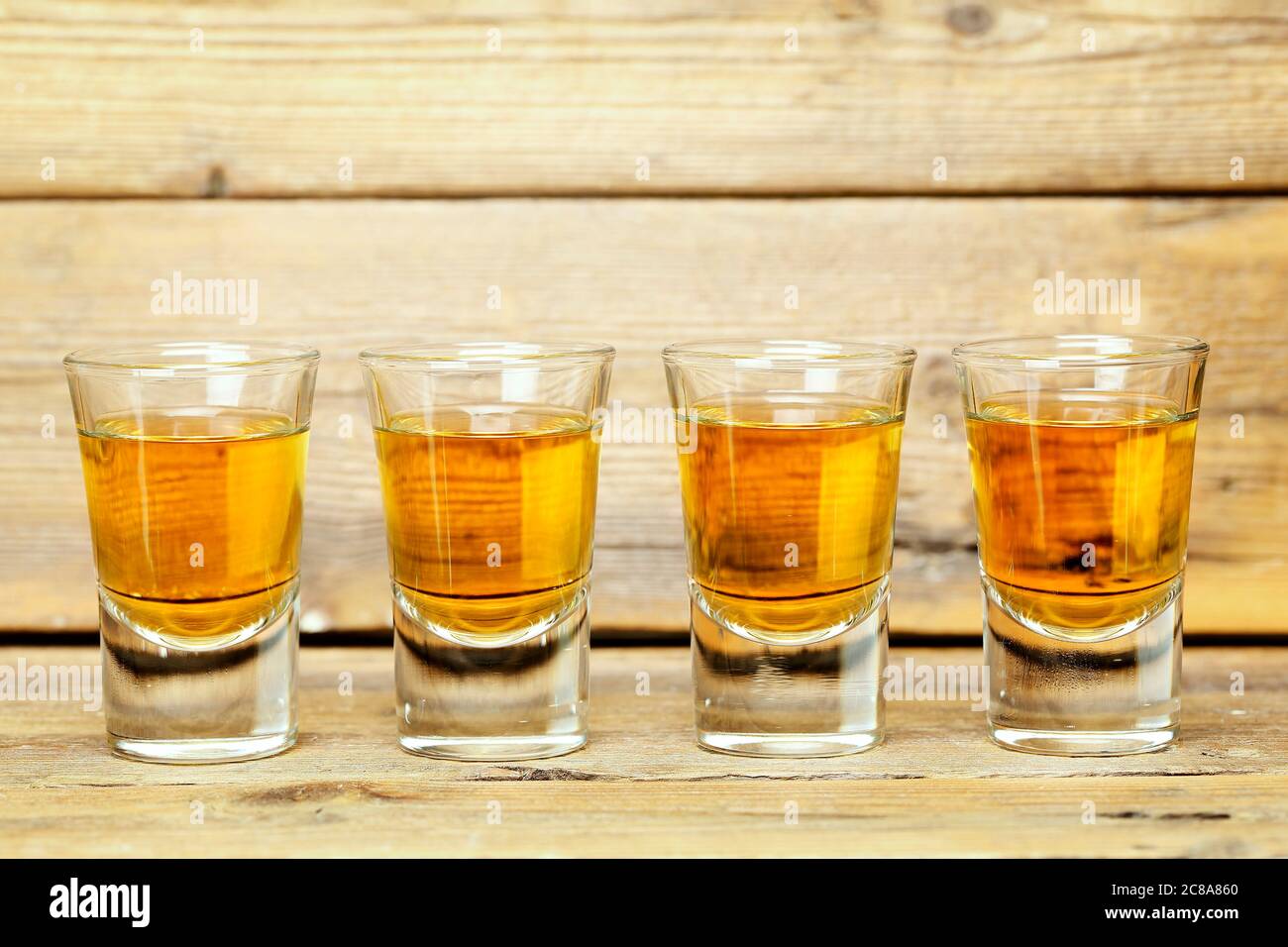 closeup of four whiskey shots on weathered wooden planks Stock Photo