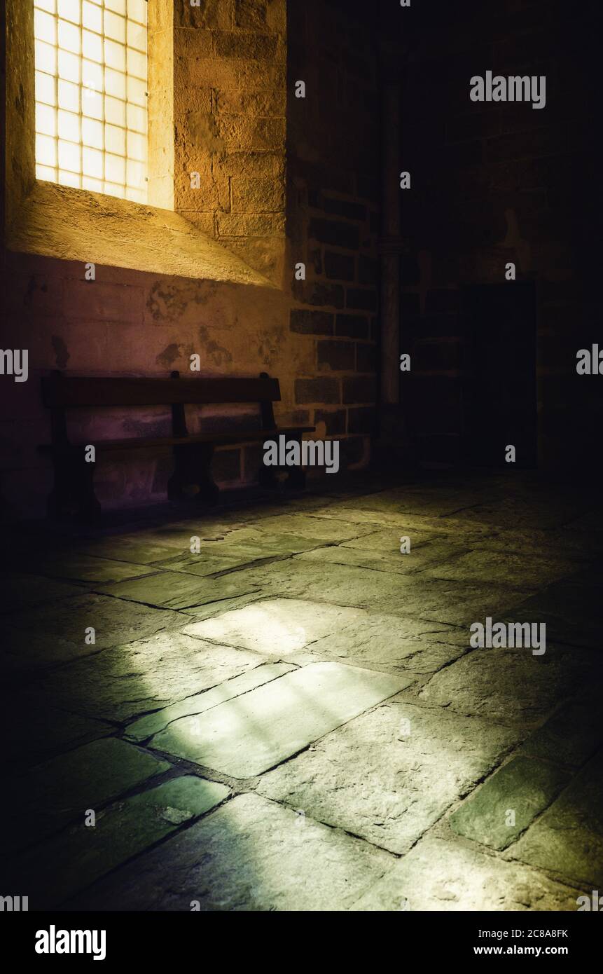 Bright yellow light from an ancient medieval window illuminates the stone floor of a romanesque monastery church Stock Photo