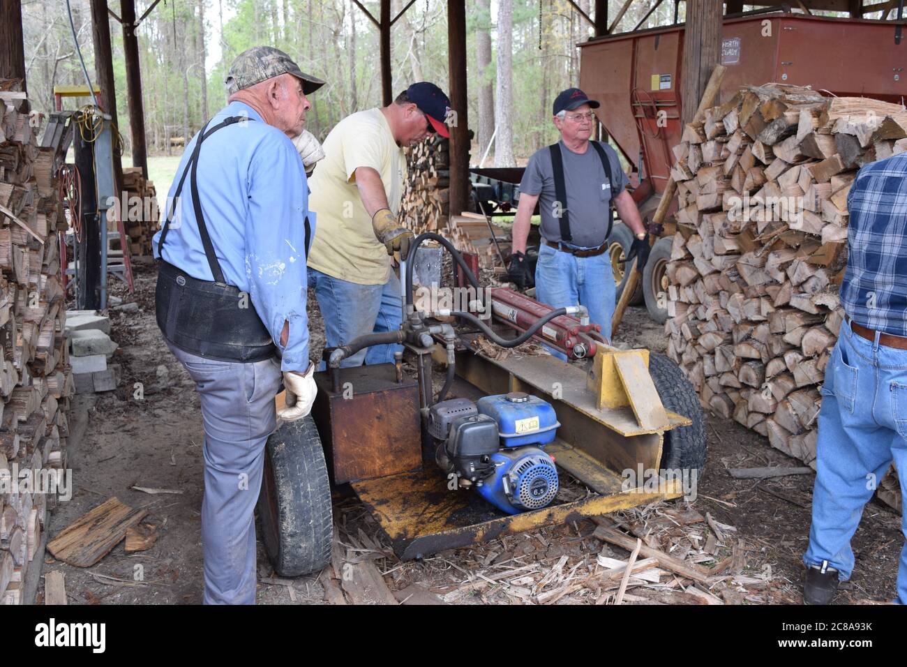 A group splitting firewood for the community Stock Photo Alamy