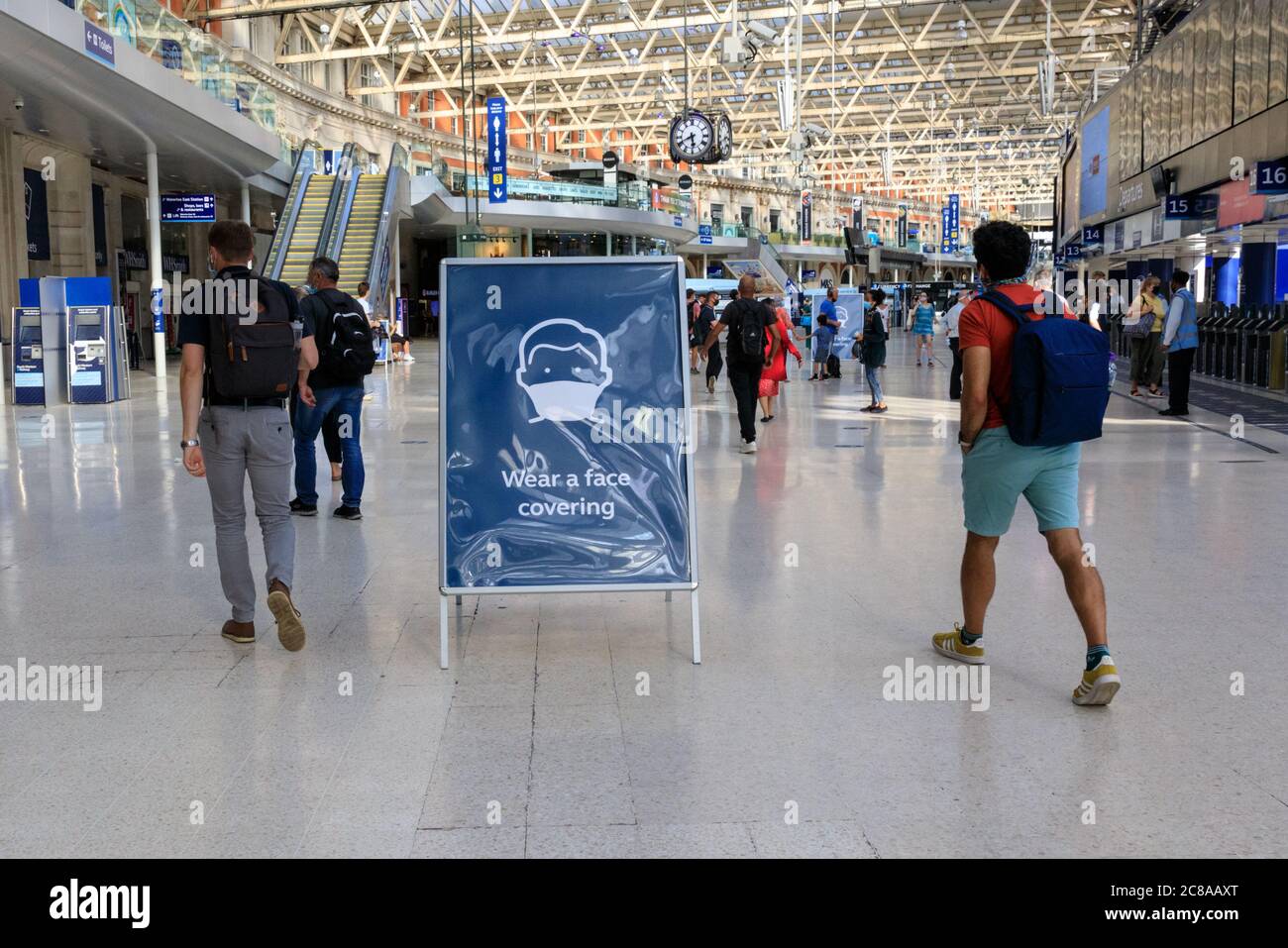 London, UK. 22nd July, 2020. A "Wear a Face Covering" sign reminds commuters inside Waterloo Station to wear their masks. Mask wearing and social distancing appear to become 'the new normal' as more and more people get used to the new guidelines and recommendations in place. Credit: Imageplotter/Alamy Live News Stock Photo