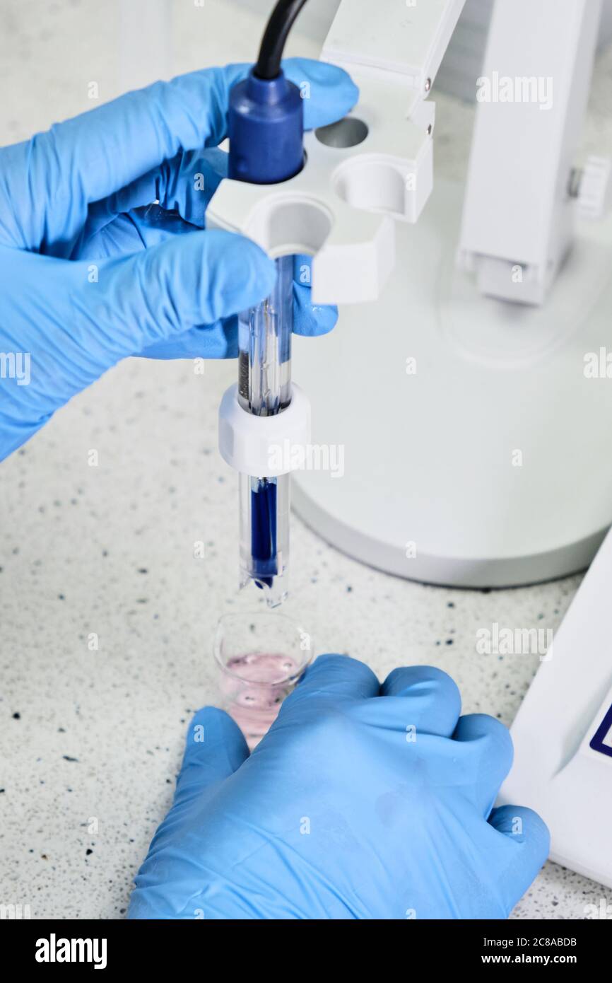Woman in a rubber gloves holding a glass electrode for measuring of pH
