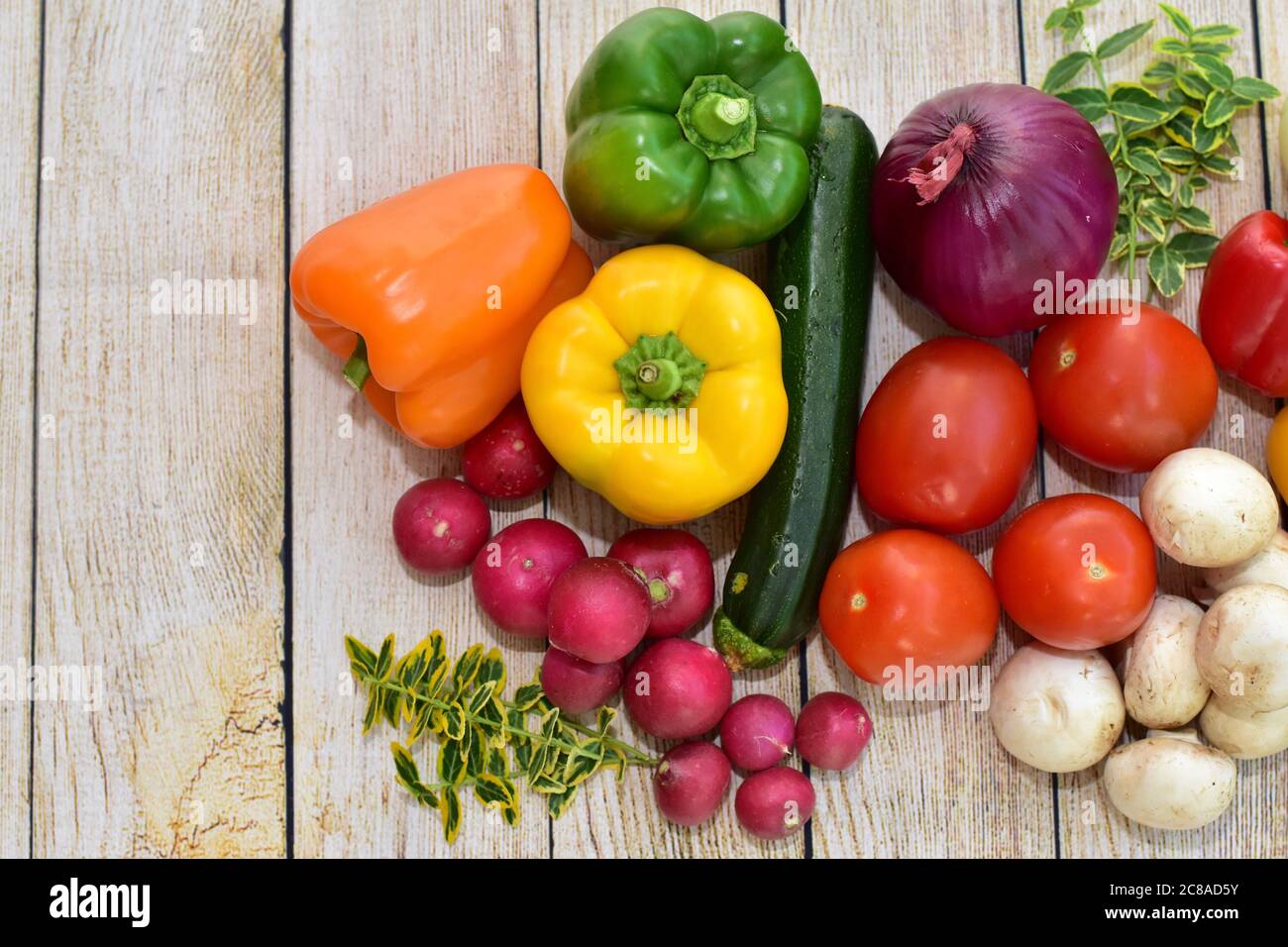 Fresh organic harvested vegetables and flowers displayed on wooden table in artistic arrangement to encourage healthy eating meals Stock Photo