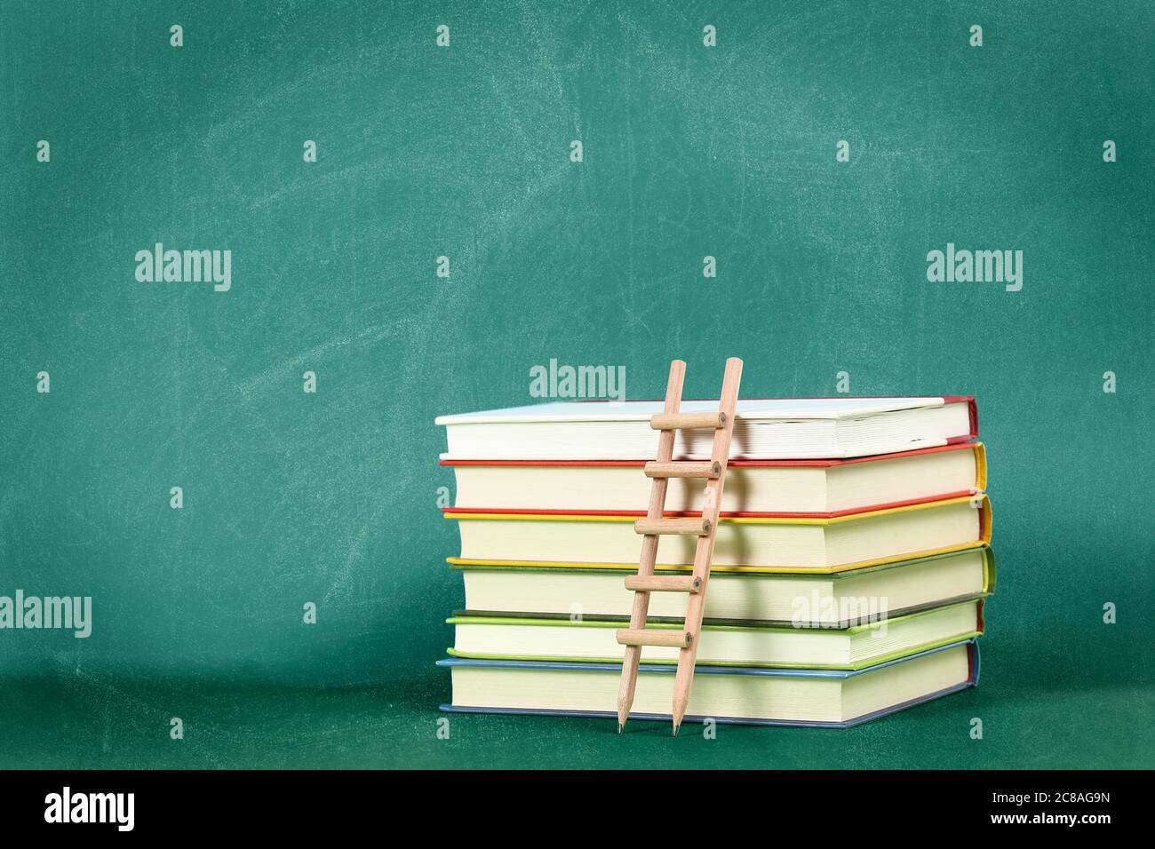 pencil ladder on stack of books against green chalkboard, education concept or background Stock Photo