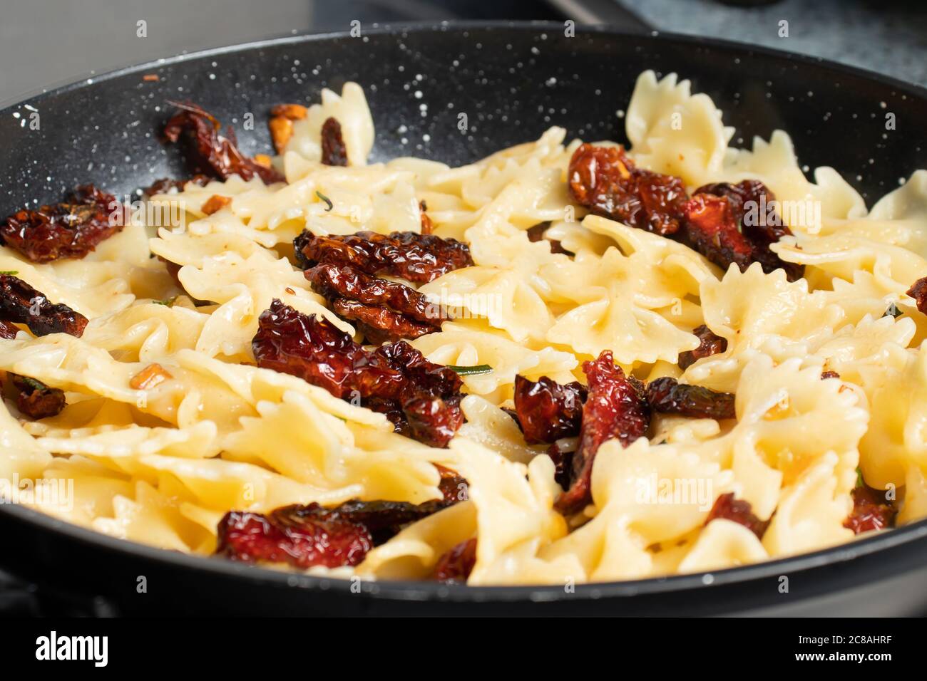Pan-fried pasta with sun-dried tomatoes and garlic. Stages of cooking Italian cuisine Stock Photo