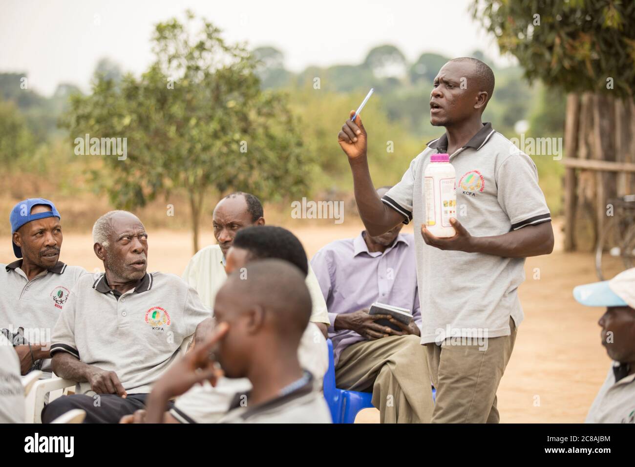 An agricultural extension worker educates small farmers and sells them farming inputs at a village community meeting in Kyotera District, Uganda. Stock Photo