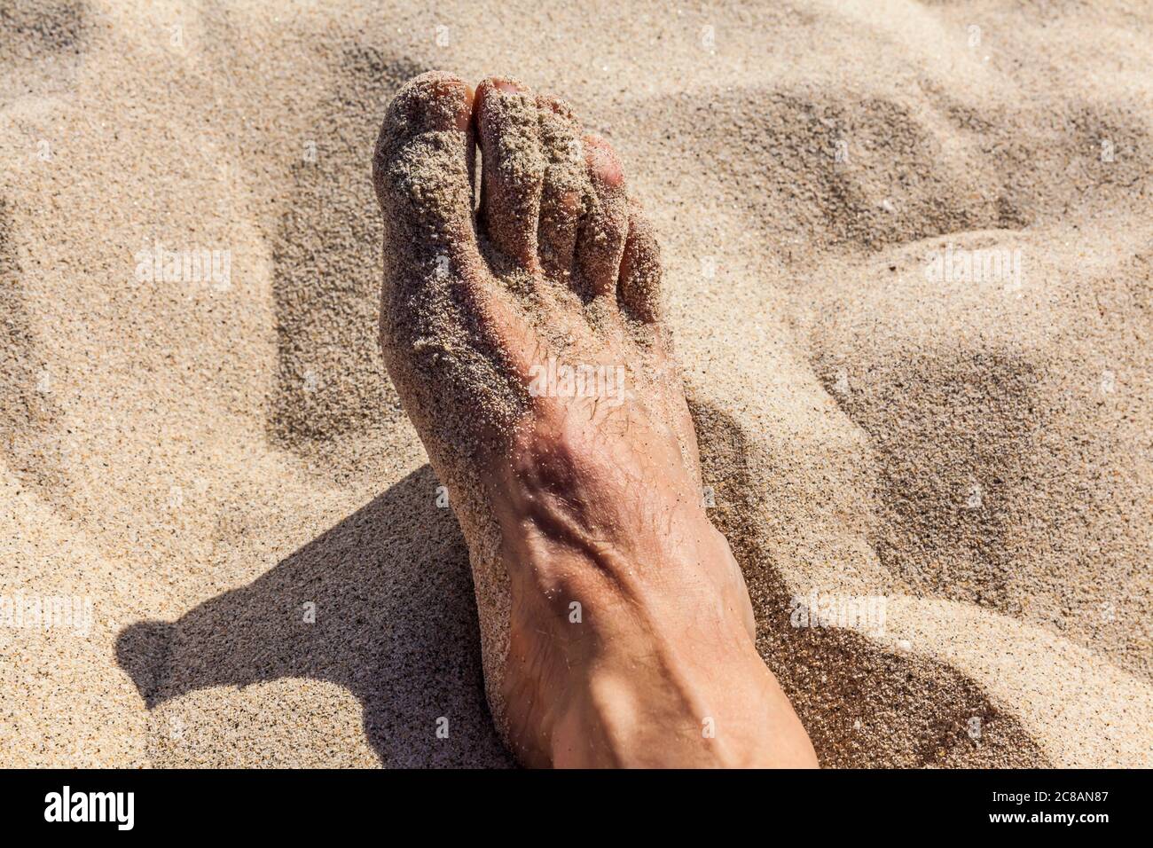 A closeup view of a man's foot in the sand. Stock Photo