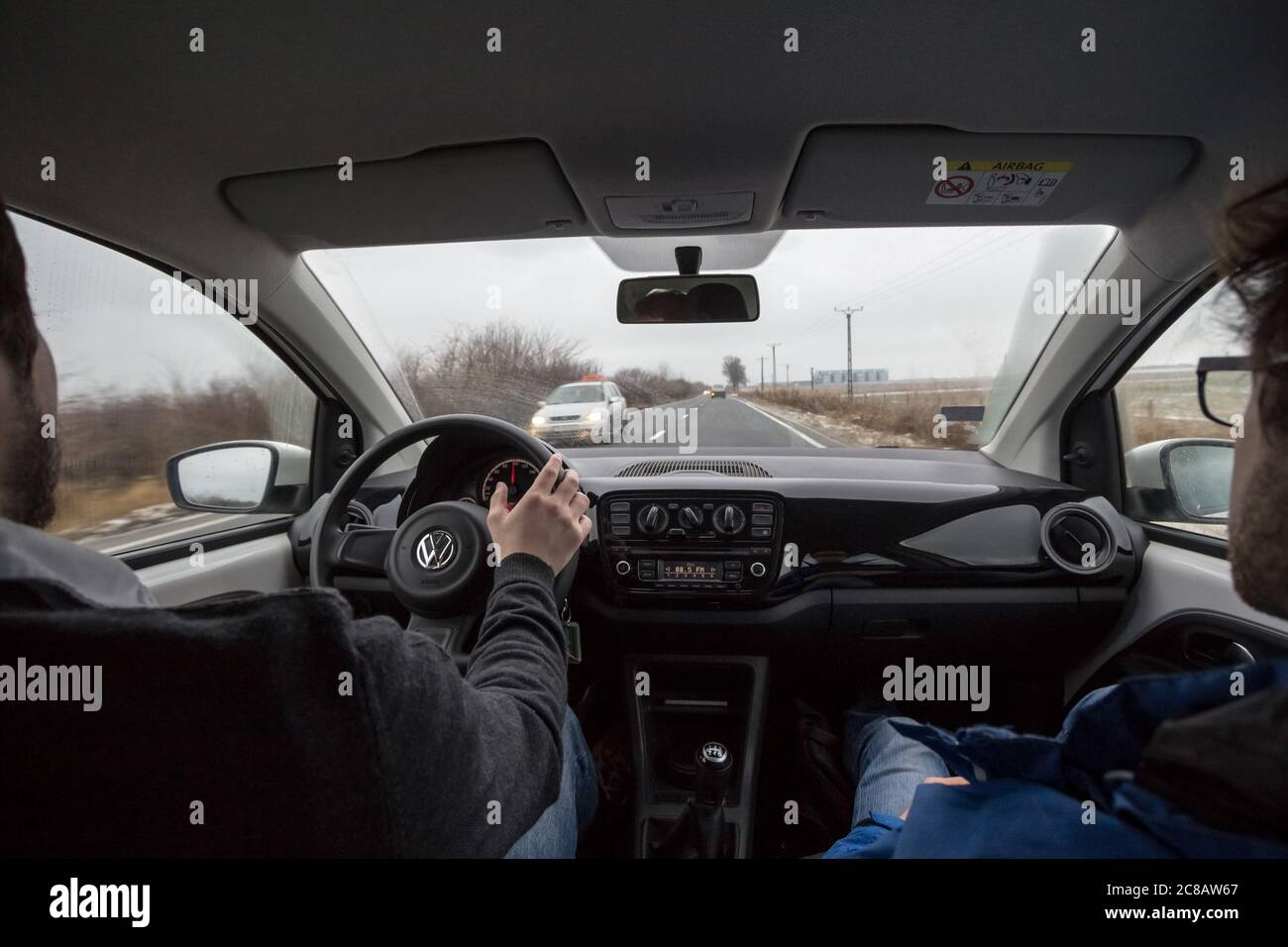 TIMISOARA, ROMANIA - JANUARY 14, 2017: Man driving a Volkswagen car with its logo, hands on the steering wheel, with a friend as a copilot and a stere Stock Photo