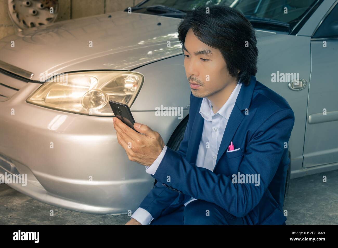 Asian Insurance Agent or Insurance Agency in Suit See Smartphone and Inspecting Car Crash from Accident for Claim at Outdoor Place in Vintage Tone Stock Photo