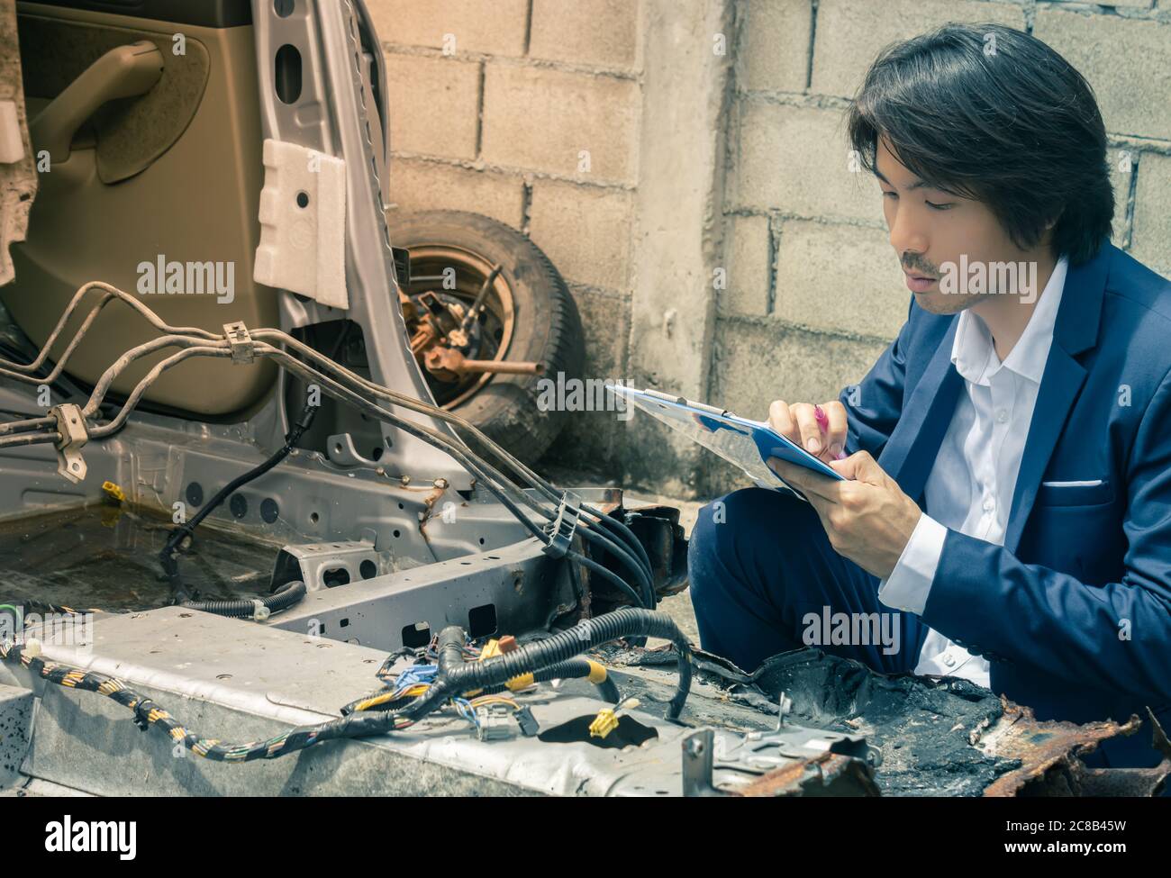 Asian Insurance Agent or Insurance Agency in Suit Inspecting Car Crash from Accident and Write Report at Side View for Insurance Claim at Outdoor Plac Stock Photo
