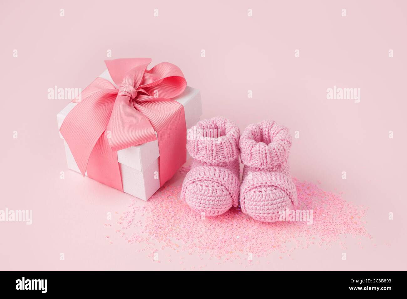 Pair of small pink baby socks and gift box on pink background with copy ...
