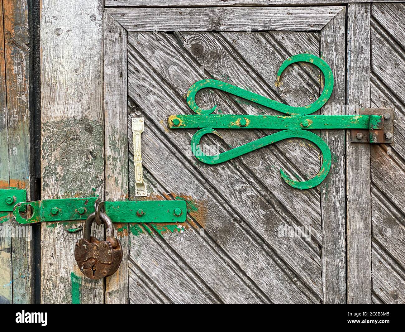 closed old fashioned wooden door with decorative hinge and rusty