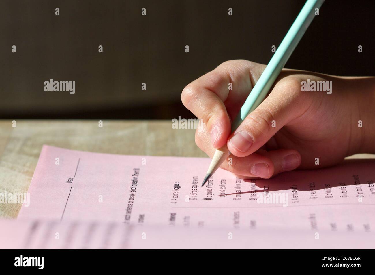 Closeup of kid's hand holding a pencil writing on a workbook. Stock Photo