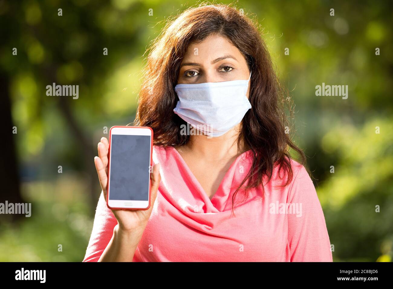 Mid adult woman showing mobile screen at park outdoor Stock Photo