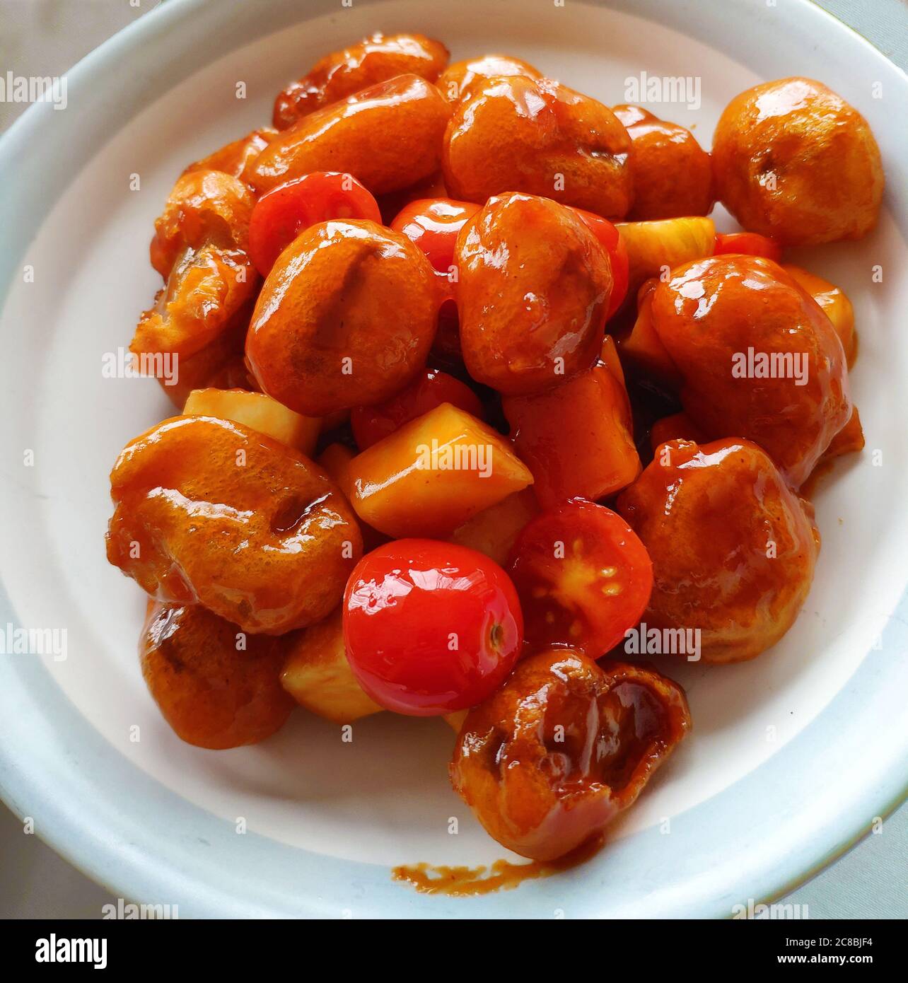 The Chinese traditional cuisine, Sweet and Sour Pork with tomato and pine apple in the white plate Stock Photo