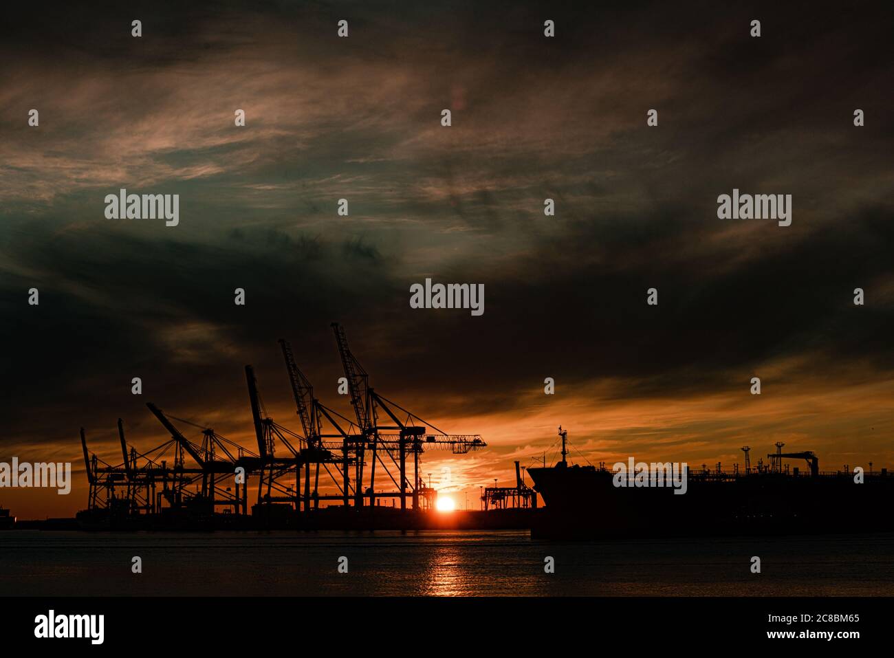 A large ship and container cranes at sunset Stock Photo - Alamy