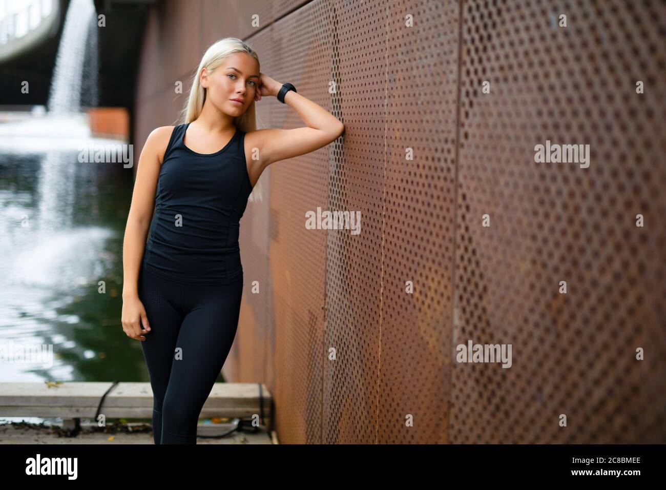 Beautiful Fit Woman in Sportswear Leaning On Metallic Wall After Workout Stock Photo