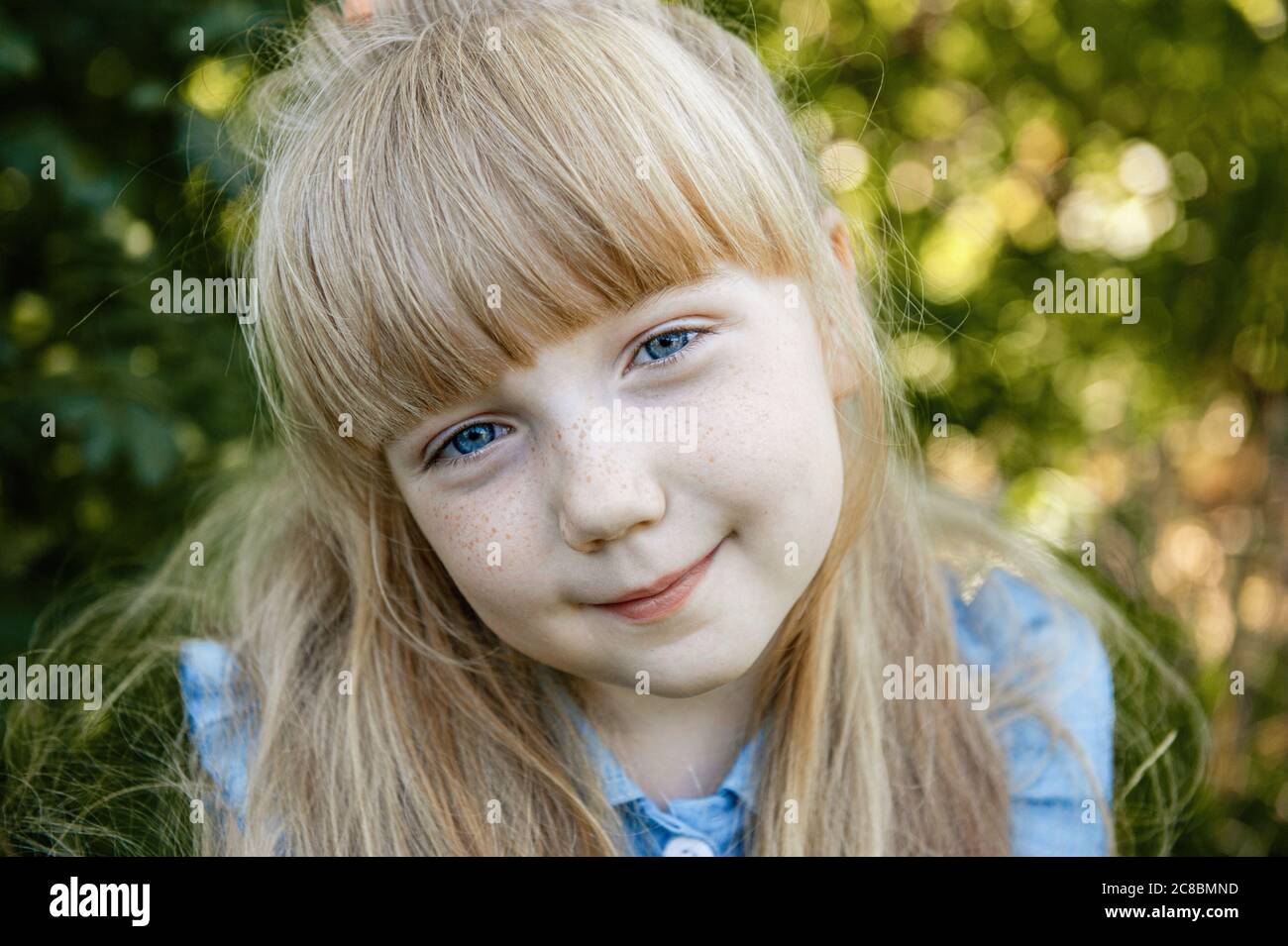 charming little girl with blue eyes and long Golden hair is smiling. Happy funny child. Stock Photo