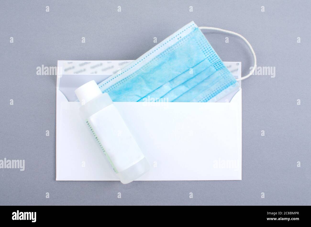 surgical mask inside a white envelope and hydroalcoolique ice jar.  waterless hand cleaning. Gray background. Stock Photo