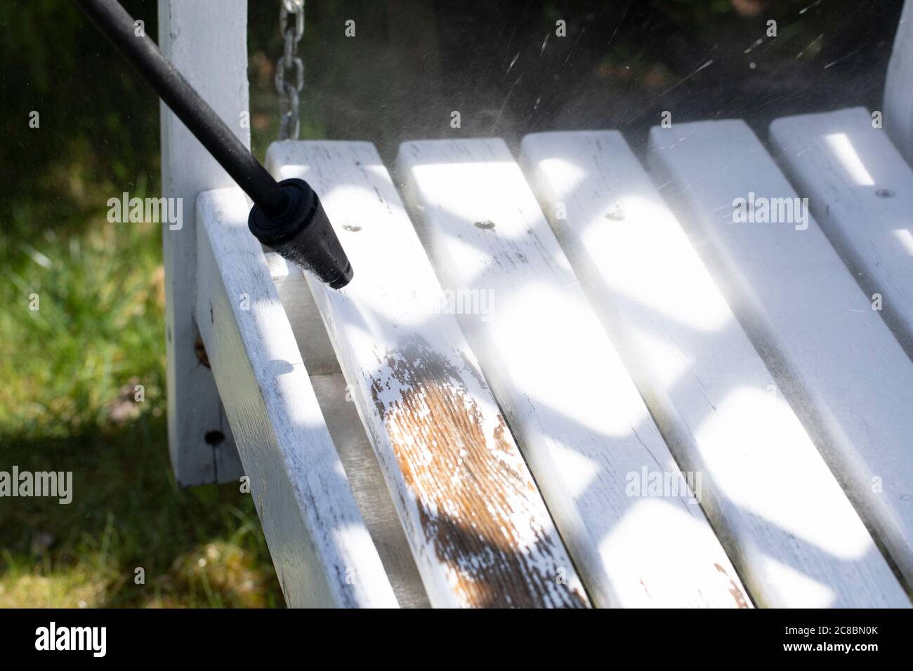 sprayer of highpressure washer scraps paint off bench in country house