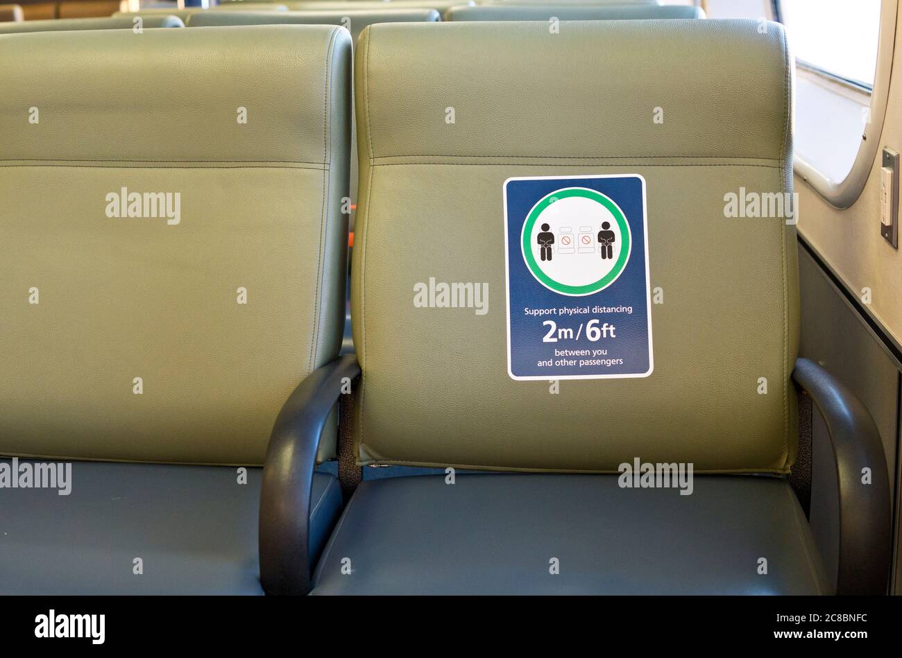Sign promoting social distancing during the Covid 19 pandemic on a seat on a BC Ferries vessel traveling from Vancouver Island. Stock Photo