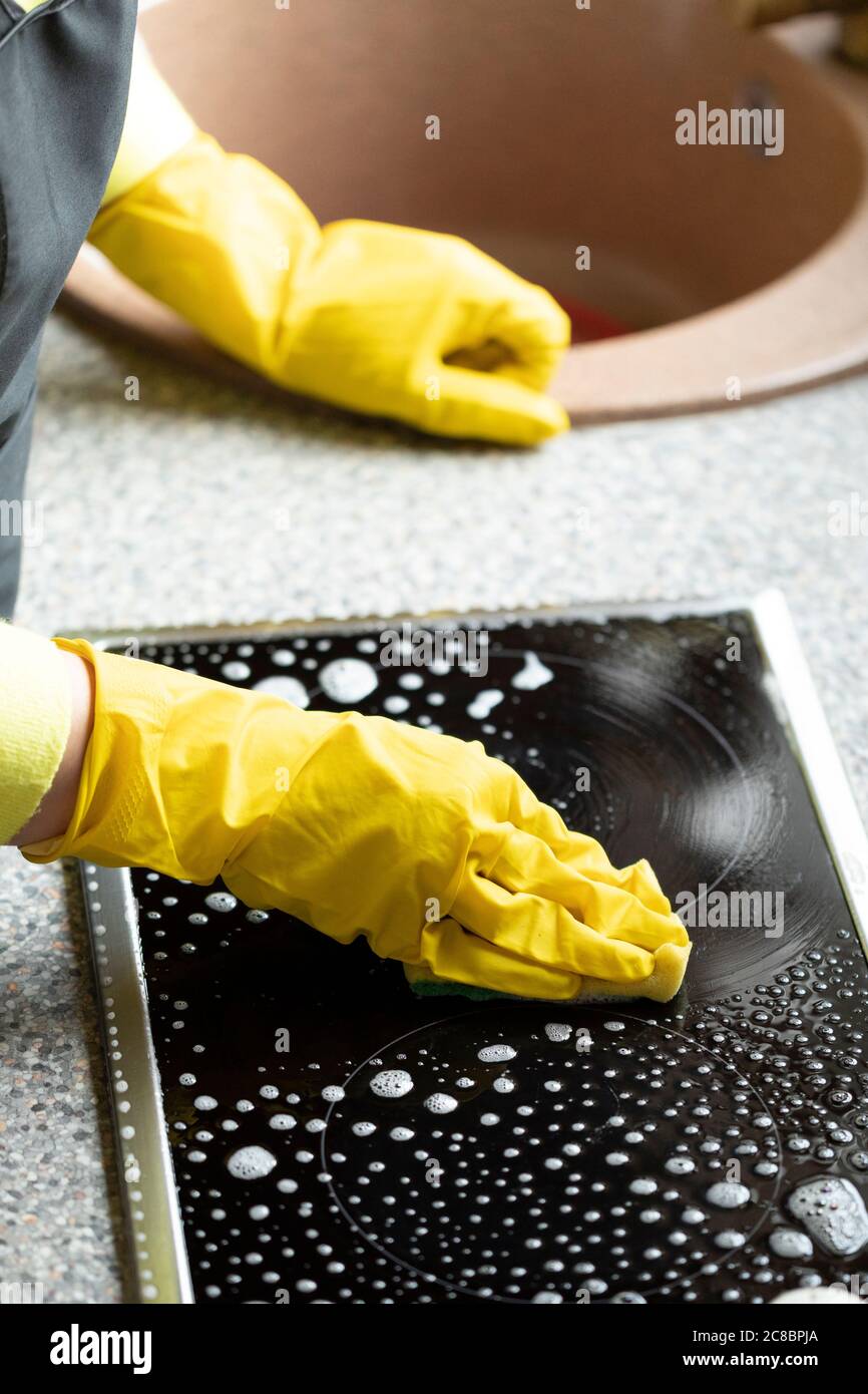 Person wipes kitchen worktop using degreaser spray detergent stove