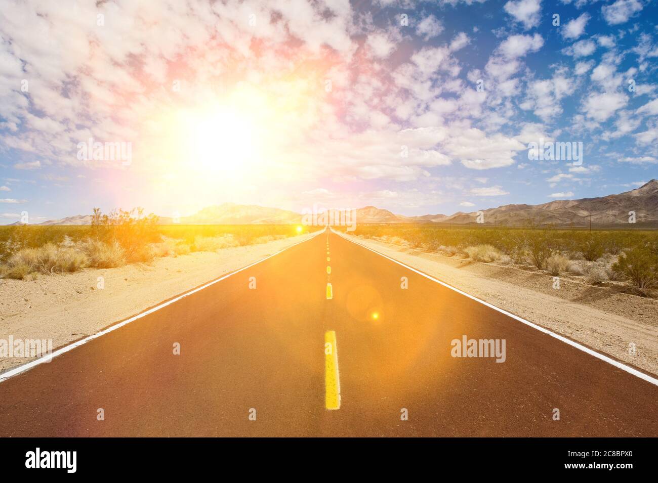 Straight desert road with strong sunshine Stock Photo