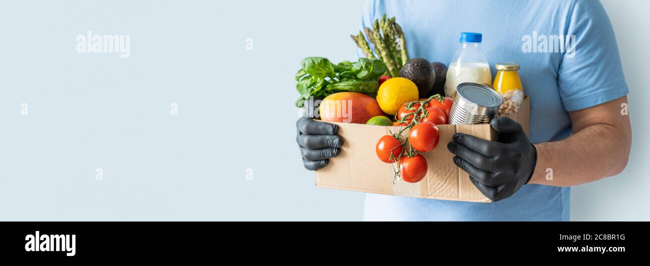 Safe food delivery concept - delivery man holds gloceries Stock Photo