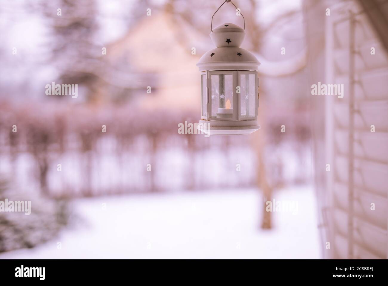 Idyllic winter view from window with cozy lantern. Iron  lantern on windowsill on background winter landscape. Lantern on windowsill. Stock Photo