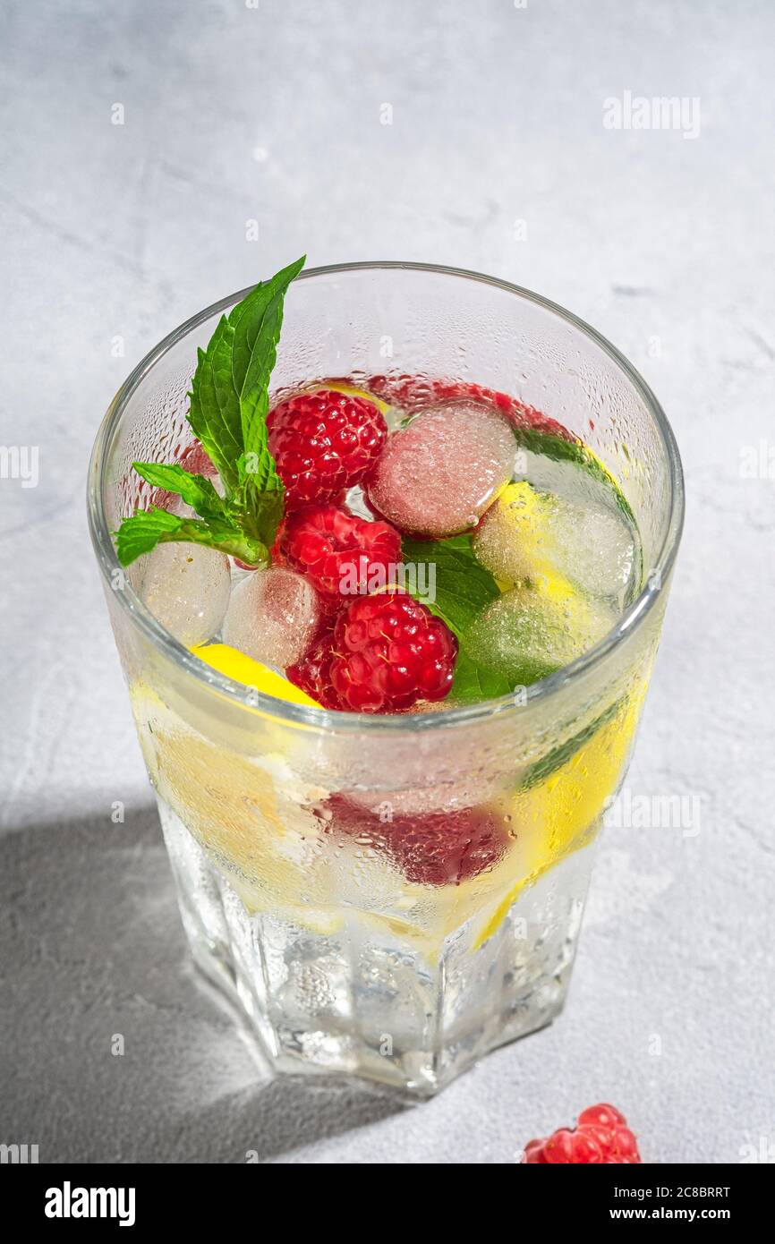 Fresh cold ice water drink with lemon, raspberry fruits and mint leaf ...
