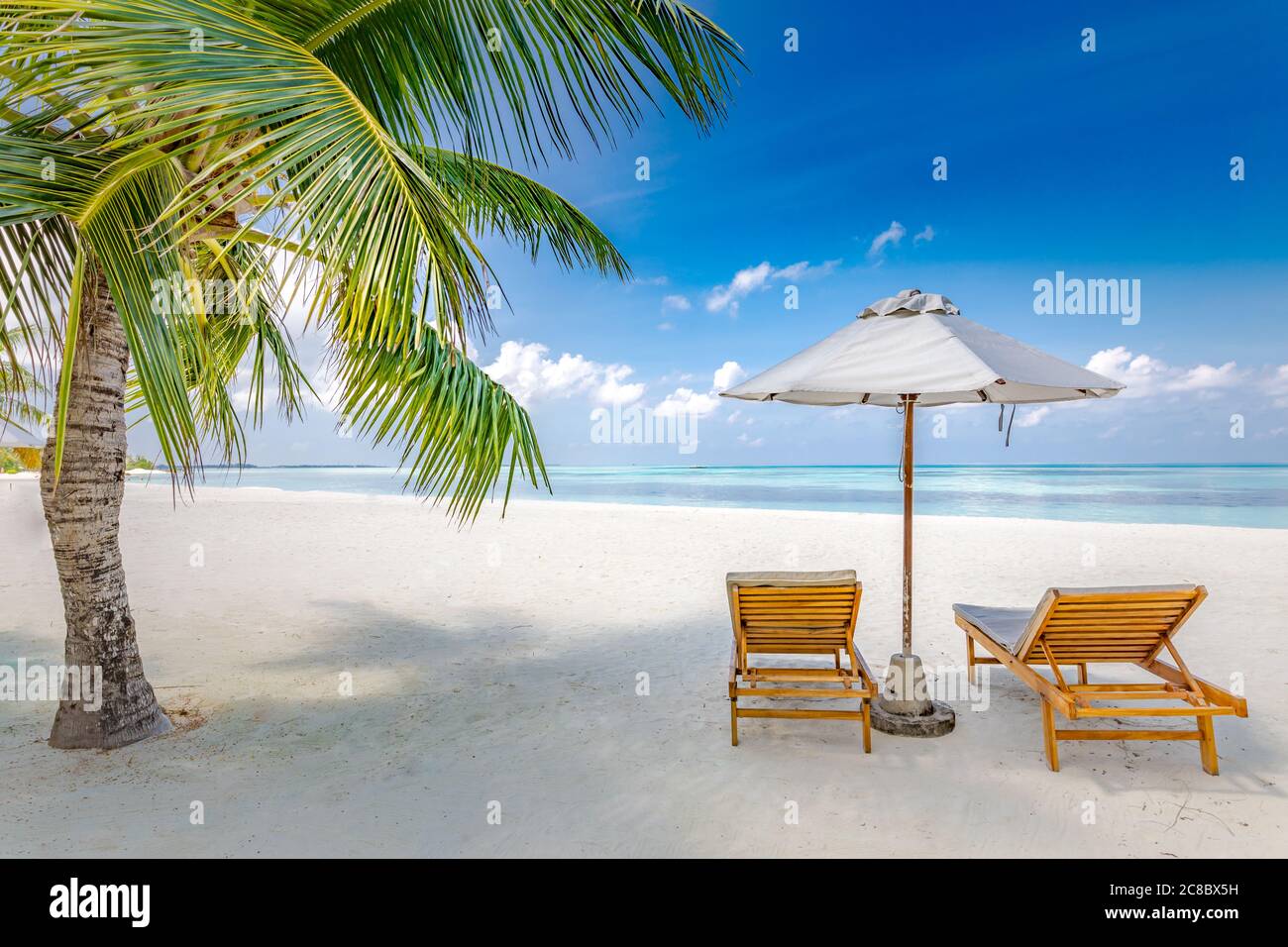 Tropical beach resort hotel background as summer landscape with lounge chairs and palm trees in sun rays calm sea for beach banner. Luxury vacation Stock Photo